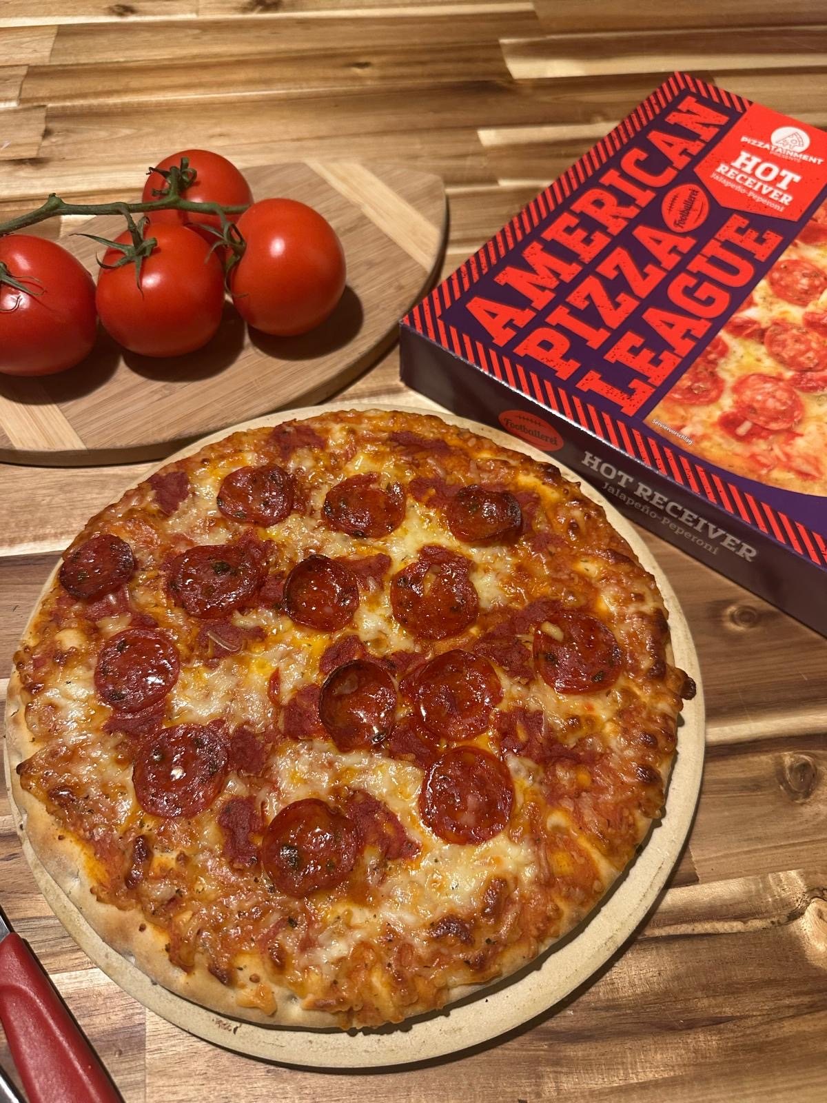Gebackene Hot-Receiver-Pizza mit Salami neben der Packung der American Pizza League