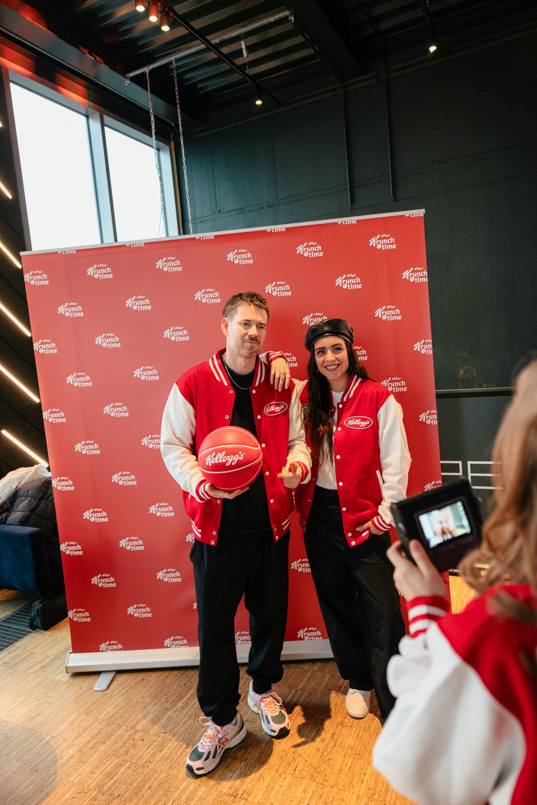 Zwei Creator*innen mit Kellogg’s-Basketball vor der Fotowand
