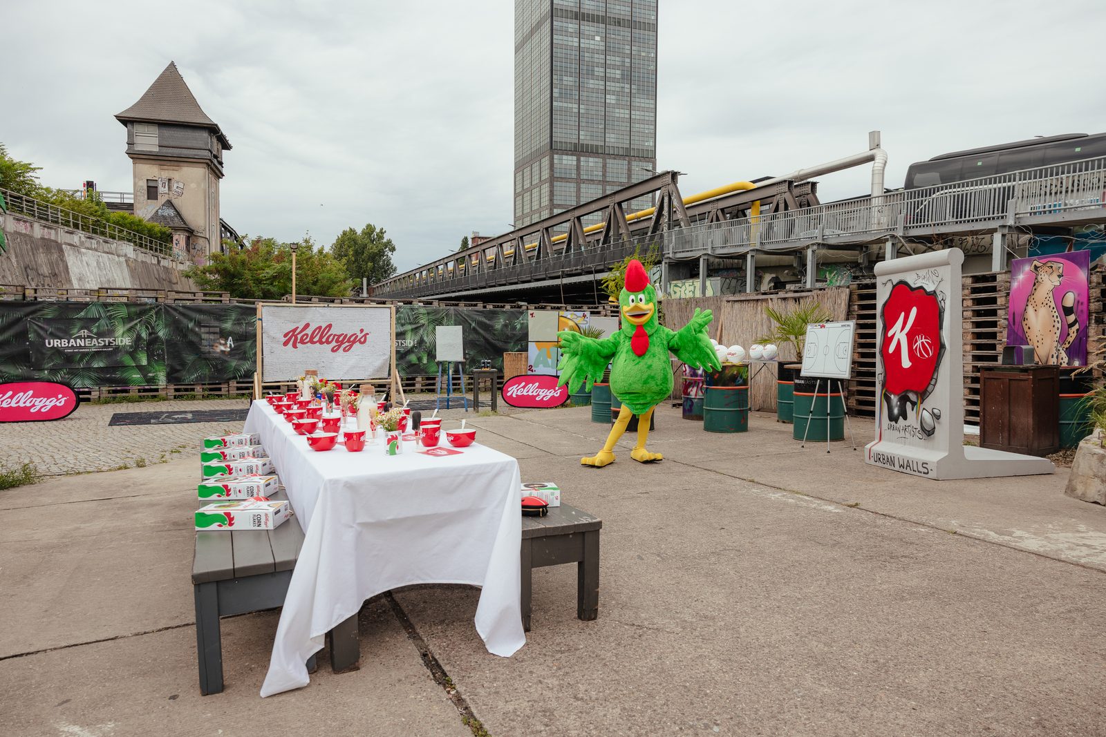 Gedeckte Frühstückstafel mit Kellogg's-Branding im Hinterhof, daneben das Maskottchen