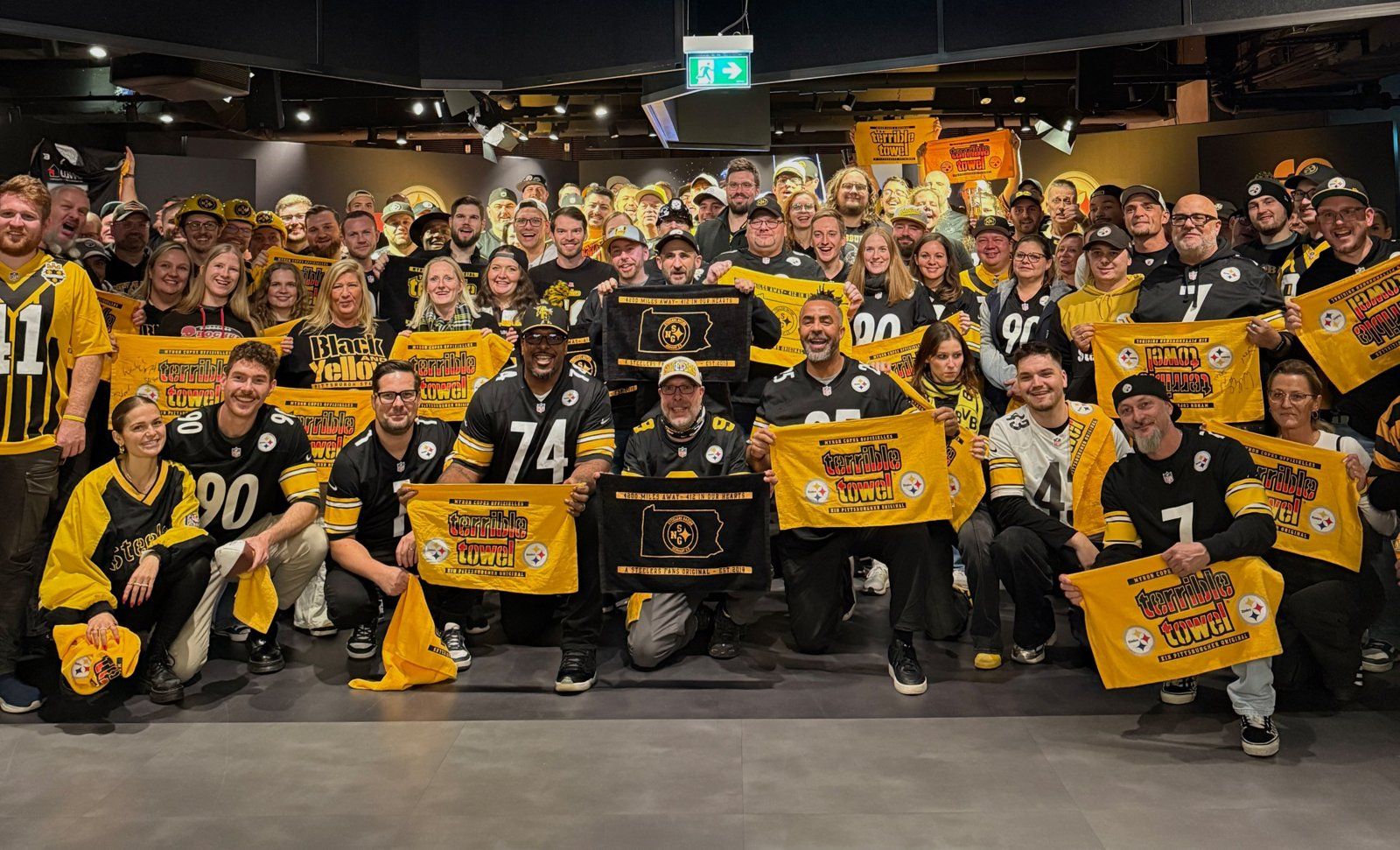 Großes Gruppenfoto von Steelers-Fans in Trikots, die gelbe Terrible Towels und Fanclub-Banner hochhalten