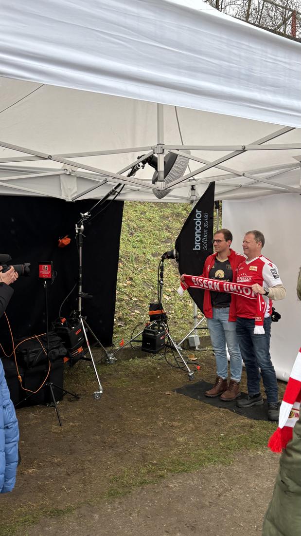 Behind-the-Scenes am Fotostudio-Zelt vor der Alten Försterei: zwei Fans im Union-Trikot posieren mit „Eisern Union“