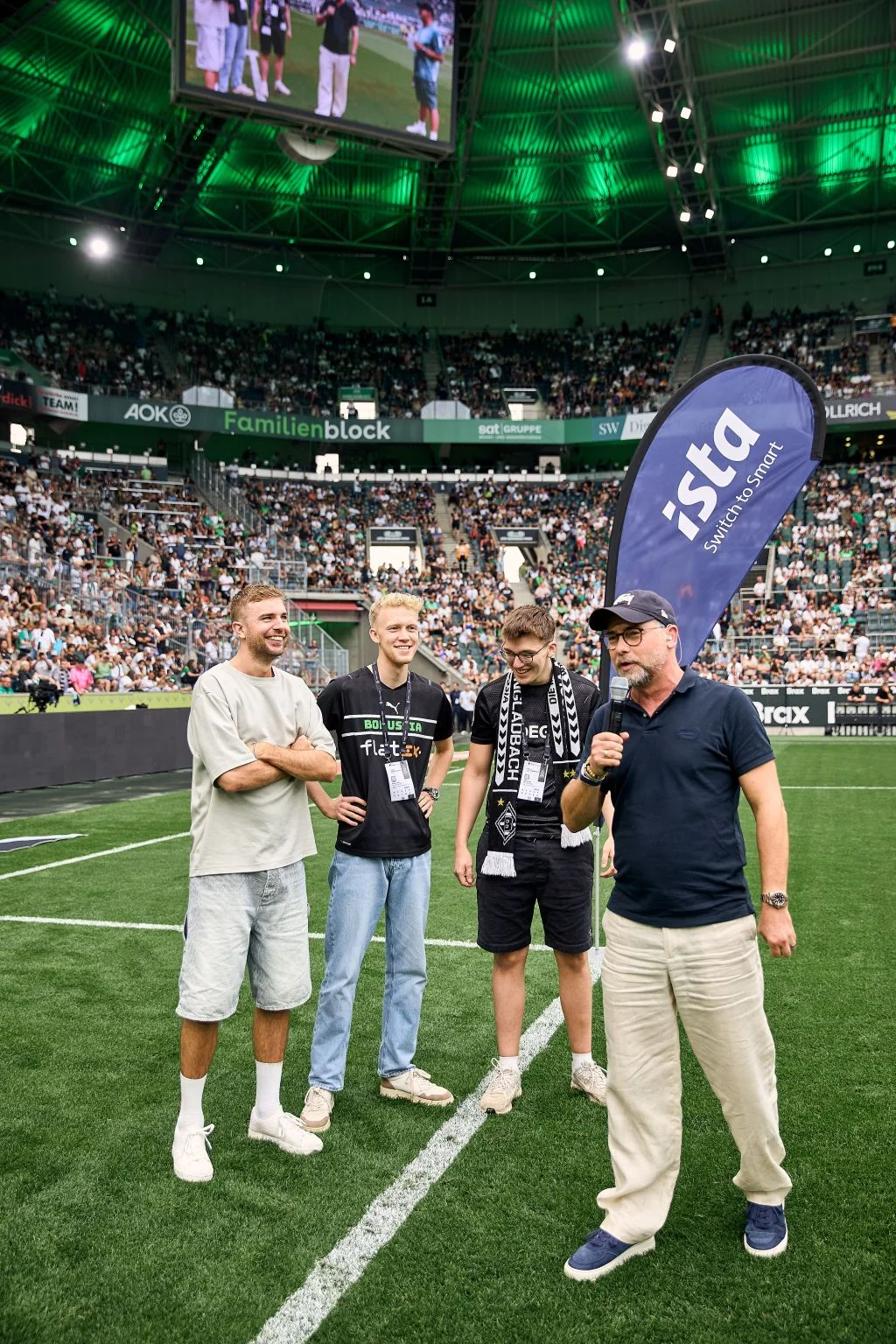 Interview auf dem Rasen vor voller Tribüne, daneben eine ista-Beachflag