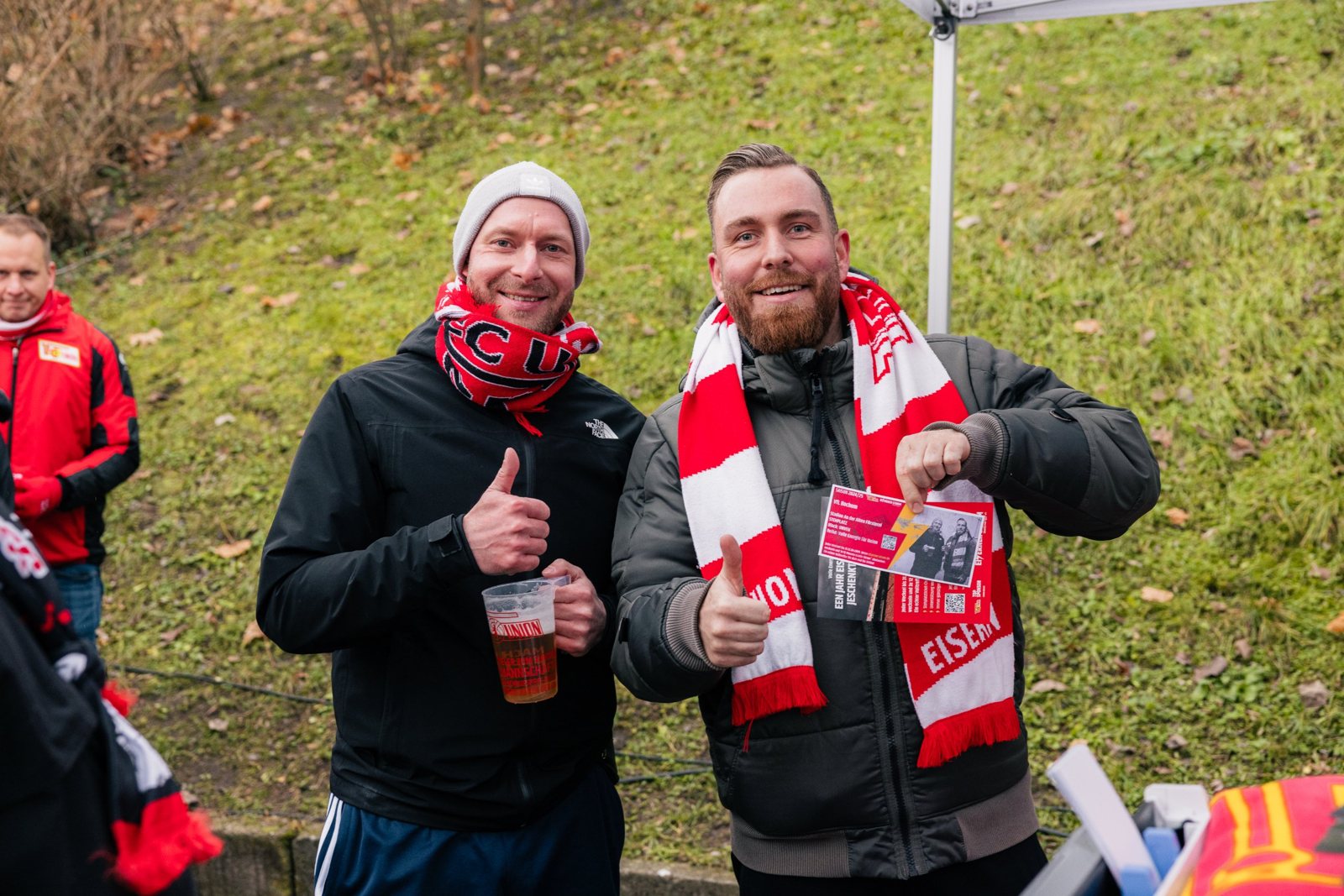 Zwei Union-Fans mit Schal zeigen ihr personalisiertes Retro-Ticket und Daumen hoch