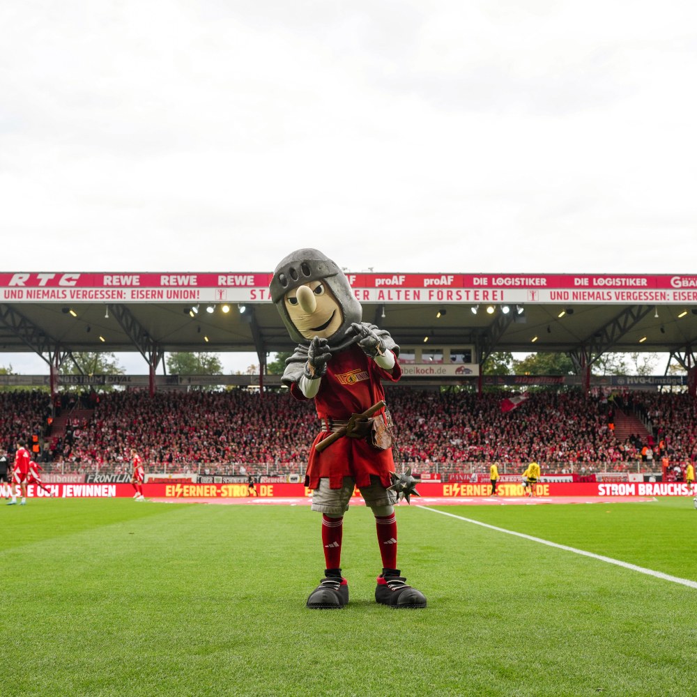 Union-Maskottchen Ritter Keule auf dem Rasen der Alten Försterei vor voller Tribüne