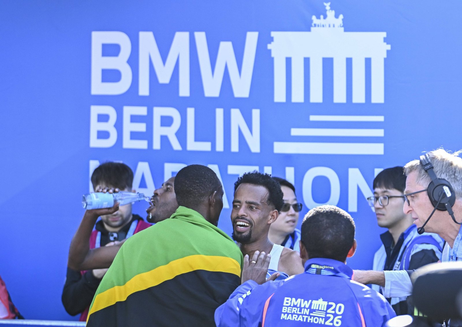 Läufer feiern im Ziel vor der Wand mit dem Logo des BMW Berlin-Marathons