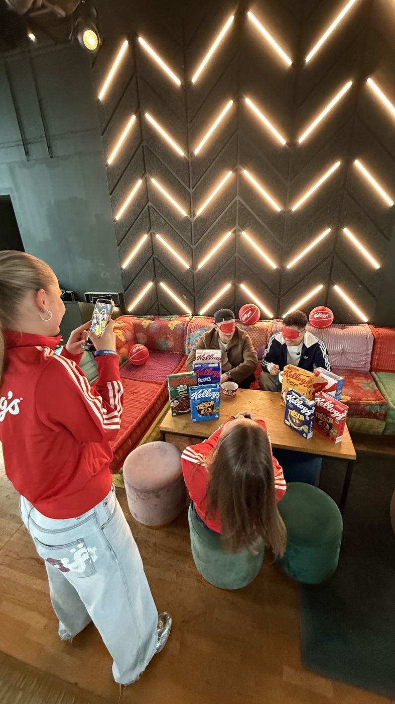 Creatorin in roter Kellogg’s-Jacke beim Creator-Event in einer Lounge mit Leuchtwand, im Hintergrund Gäste an Tischen