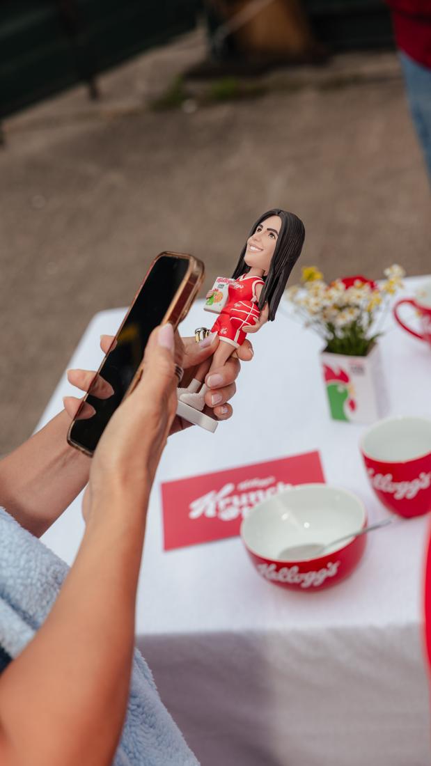 Personalisierte Bobblehead-Figur im Kellogg's-Trikot mit Cornflakes-Packung, davor Kellogg's-Schalen und Krunc